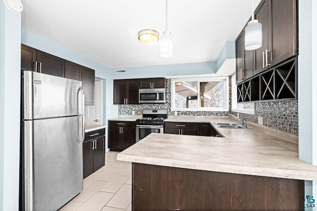 kitchen with visible vents, a sink, backsplash, stainless steel appliances, and dark brown cabinetry