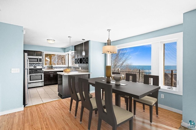 dining space featuring light wood-type flooring and baseboards