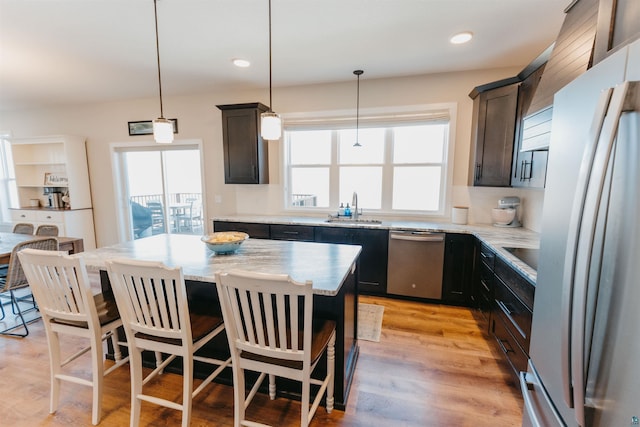 kitchen featuring a sink, stainless steel appliances, a kitchen breakfast bar, and light wood-style floors