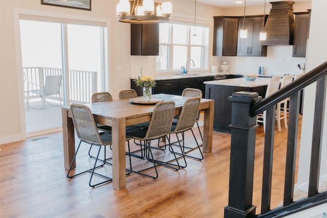 dining room featuring light wood finished floors, visible vents, baseboards, stairs, and a notable chandelier