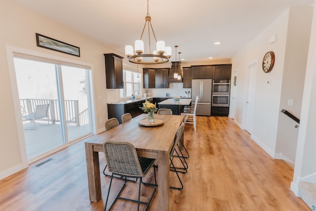 dining area with visible vents, light wood-style flooring, recessed lighting, an inviting chandelier, and baseboards