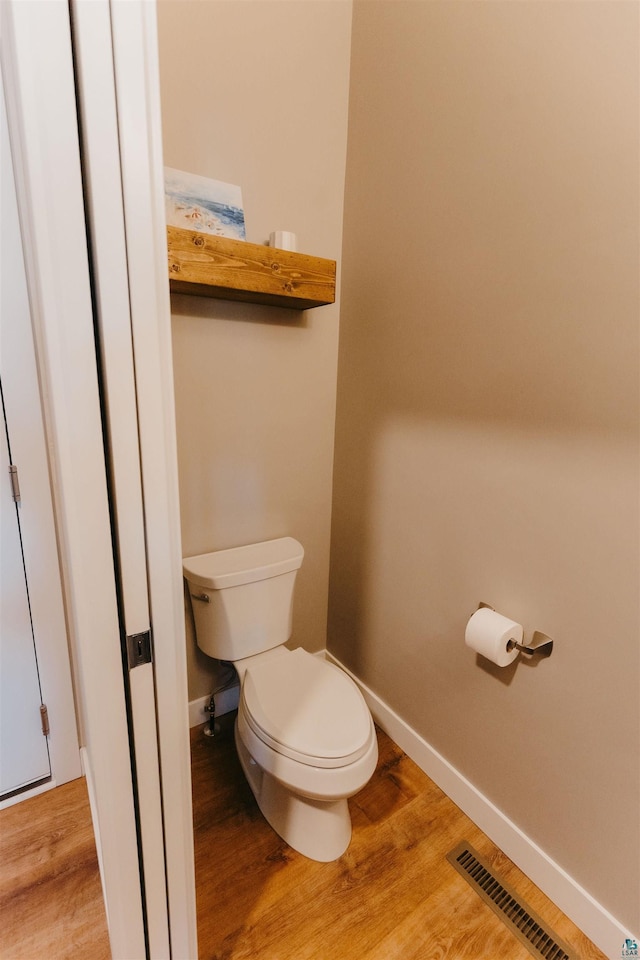 bathroom featuring visible vents, baseboards, toilet, and wood finished floors