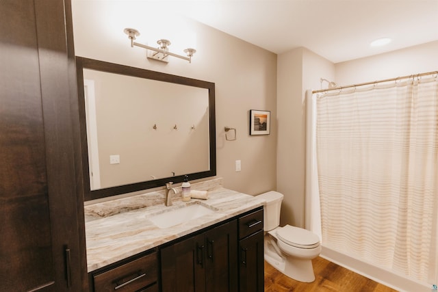 bathroom with vanity, a shower with curtain, toilet, and wood finished floors