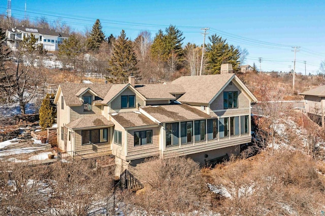 rear view of property with a chimney and a shingled roof