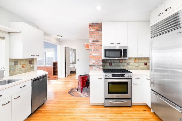 kitchen with a sink, light countertops, light wood-type flooring, and stainless steel appliances