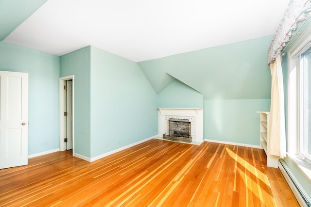 additional living space featuring wood finished floors, a fireplace, baseboards, and a baseboard radiator