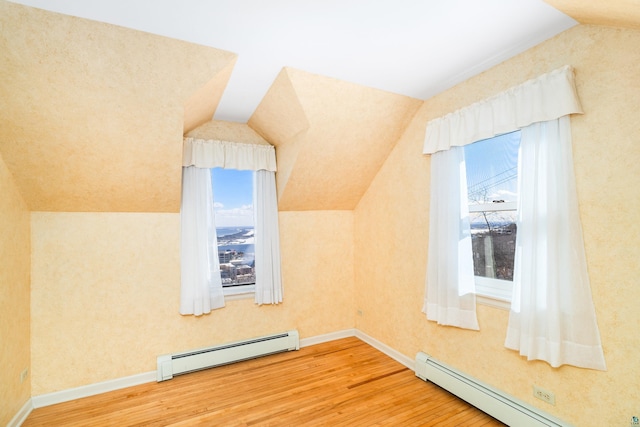 additional living space featuring a baseboard heating unit, lofted ceiling, baseboards, and wood finished floors