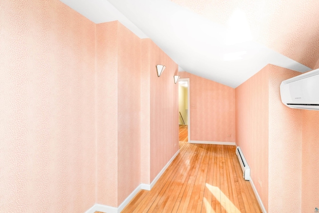 hallway with a baseboard heating unit, baseboards, a wall mounted air conditioner, lofted ceiling, and hardwood / wood-style floors