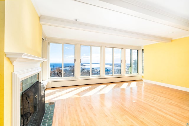 unfurnished living room featuring beamed ceiling, ornamental molding, baseboards, baseboard heating, and a tile fireplace