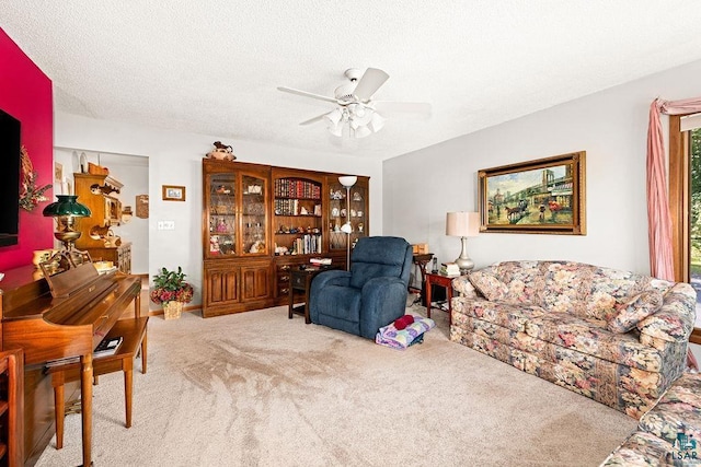 carpeted living room featuring a textured ceiling and ceiling fan