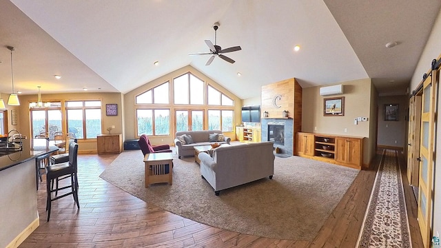 living area featuring a wall mounted AC, high vaulted ceiling, a large fireplace, and hardwood / wood-style floors