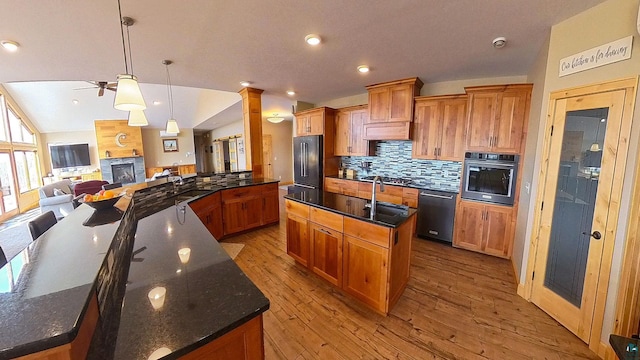 kitchen with lofted ceiling, decorative backsplash, black appliances, a large island, and open floor plan