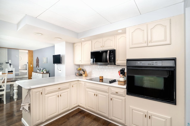 kitchen featuring light countertops, decorative backsplash, a peninsula, black appliances, and dark wood-style flooring