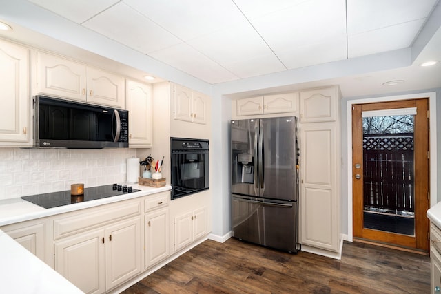 kitchen with tasteful backsplash, black appliances, dark wood-type flooring, and light countertops