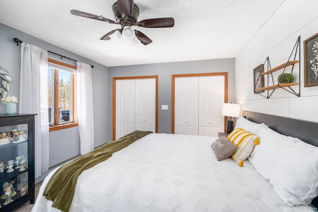 bedroom with a textured ceiling, two closets, and a ceiling fan