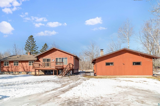 snow covered rear of property with a wooden deck