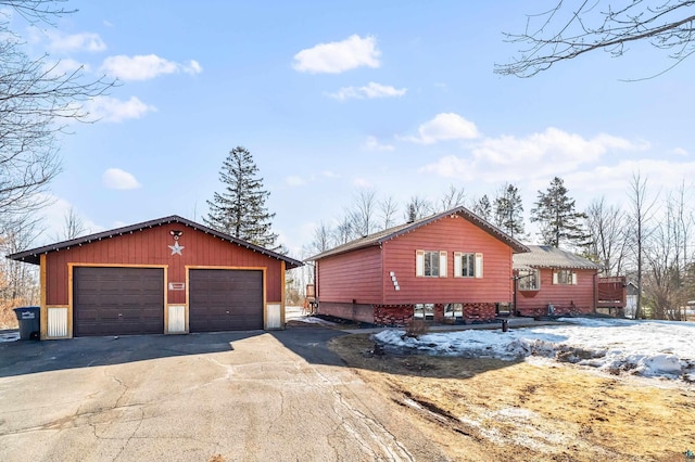 view of snowy exterior featuring a garage and an outdoor structure