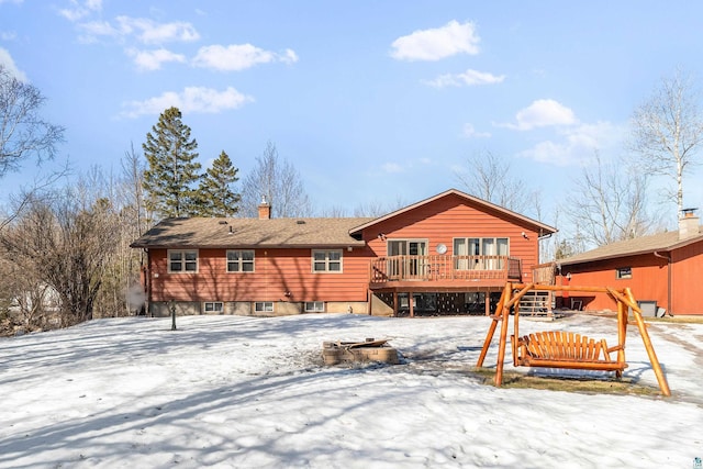 snow covered back of property featuring a deck, stairs, and a chimney