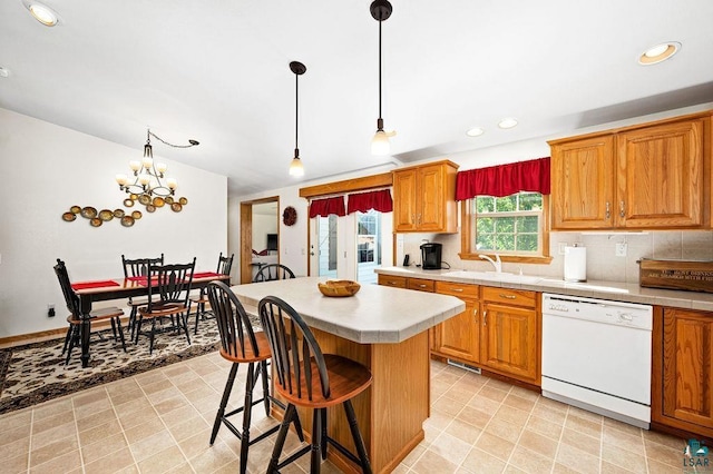 kitchen with a sink, tasteful backsplash, a center island, light countertops, and dishwasher