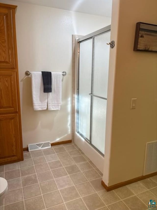 bathroom featuring tile patterned flooring, a shower stall, toilet, and visible vents