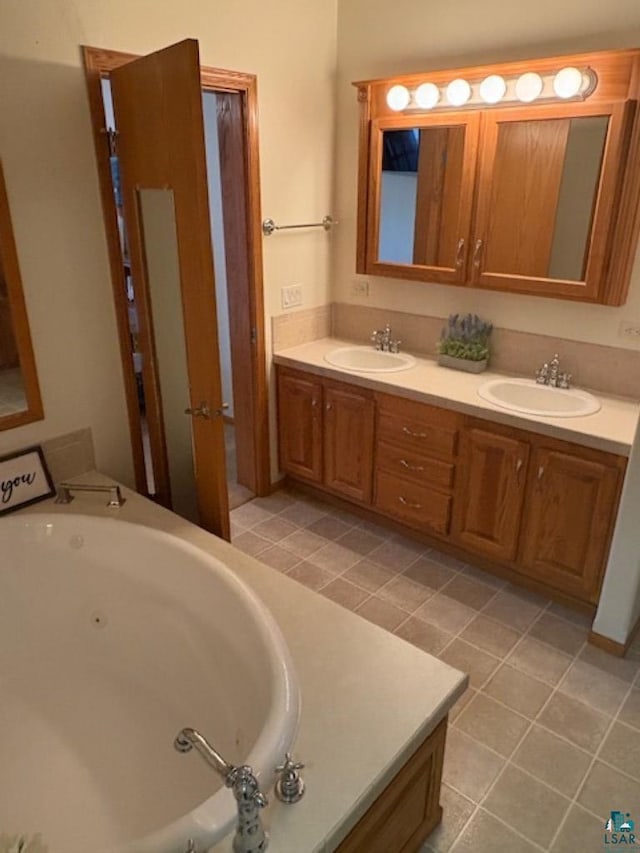 bathroom with a sink, double vanity, a whirlpool tub, and tile patterned floors