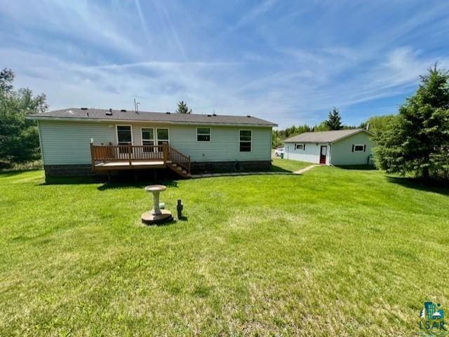 rear view of house with a wooden deck and a lawn