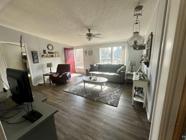 living area featuring a textured ceiling, ceiling fan, dark wood-style floors, and ornamental molding