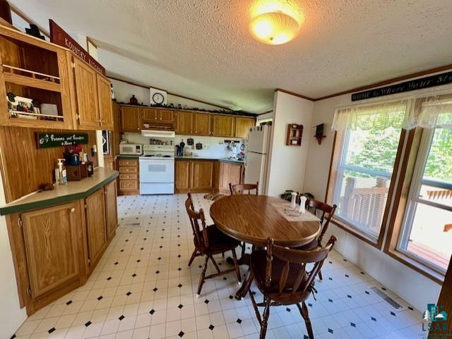 dining space featuring a textured ceiling, visible vents, light floors, and vaulted ceiling