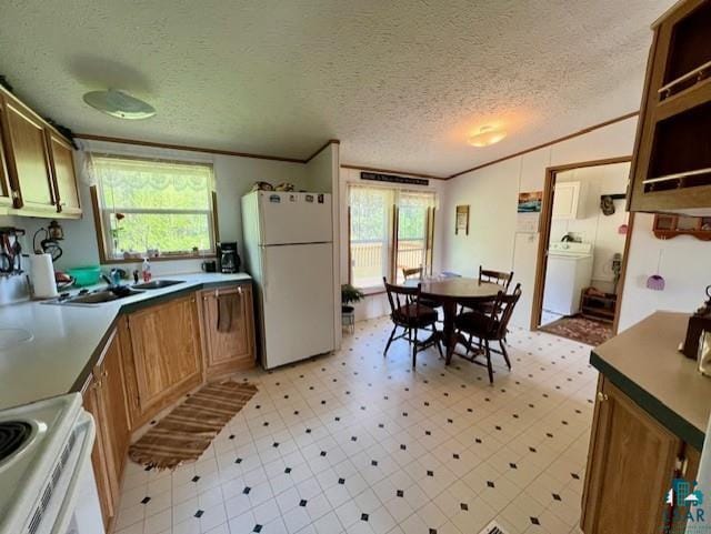 kitchen with ornamental molding, plenty of natural light, white appliances, light floors, and washer / dryer