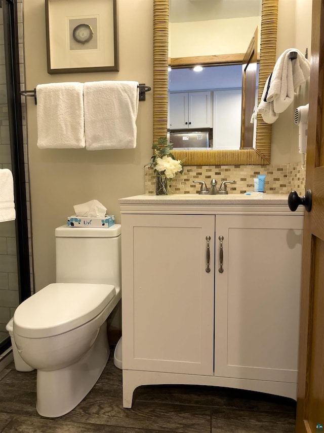 bathroom with vanity, toilet, wood finished floors, and backsplash