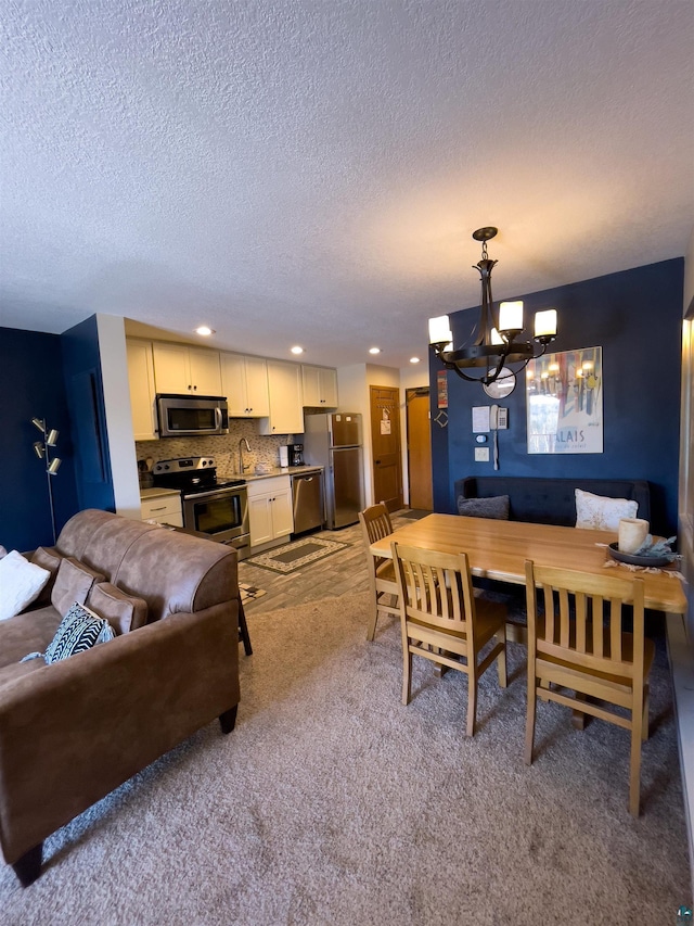 carpeted dining area with a notable chandelier, recessed lighting, a textured ceiling, and a sink