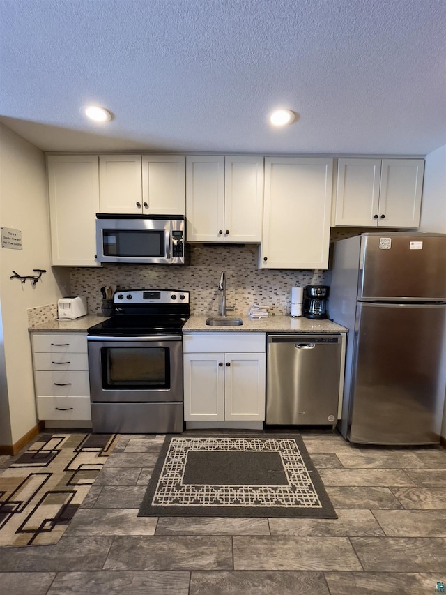 kitchen with a sink, white cabinets, tasteful backsplash, and stainless steel appliances