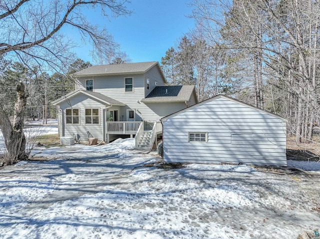 snow covered rear of property with central AC and a deck