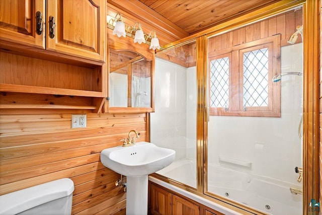 bathroom with wood ceiling, wood walls, toilet, and bath / shower combo with glass door