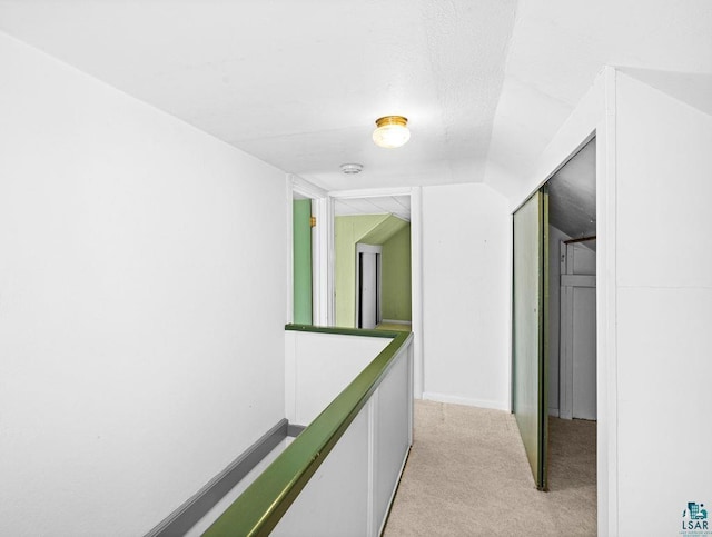 hallway featuring light colored carpet and lofted ceiling