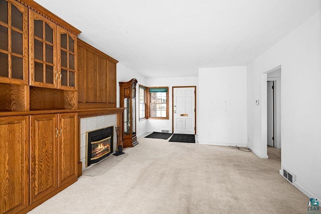 living area with visible vents, light colored carpet, a tile fireplace, and baseboards