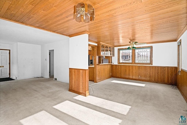 interior space featuring wooden walls, wainscoting, ceiling fan, light carpet, and wooden ceiling