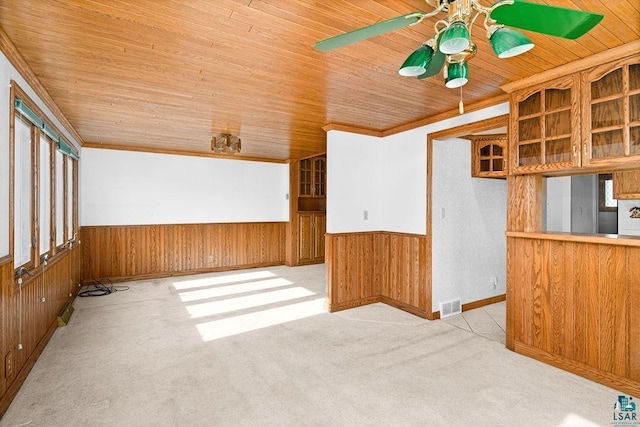 carpeted empty room with visible vents, wainscoting, wooden ceiling, and wood walls