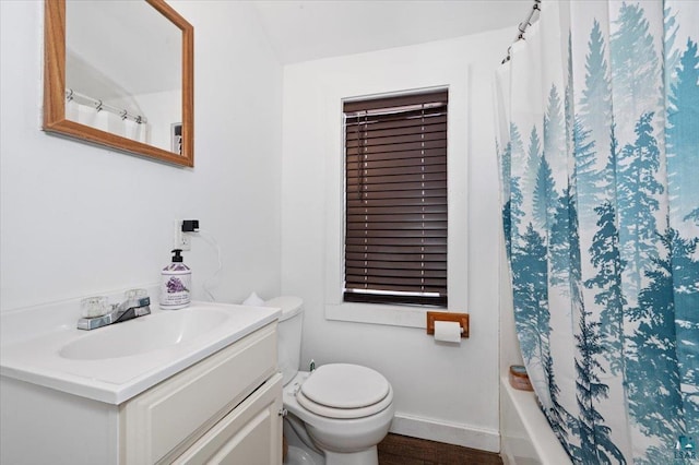 bathroom with toilet, wood finished floors, shower / tub combo, baseboards, and vanity