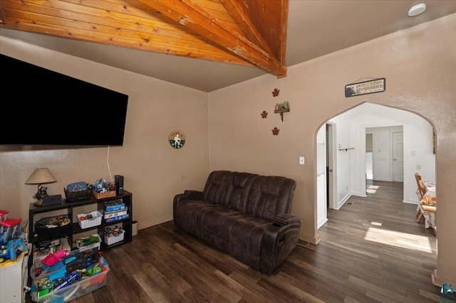 living area with beam ceiling, wood finished floors, arched walkways, and baseboards