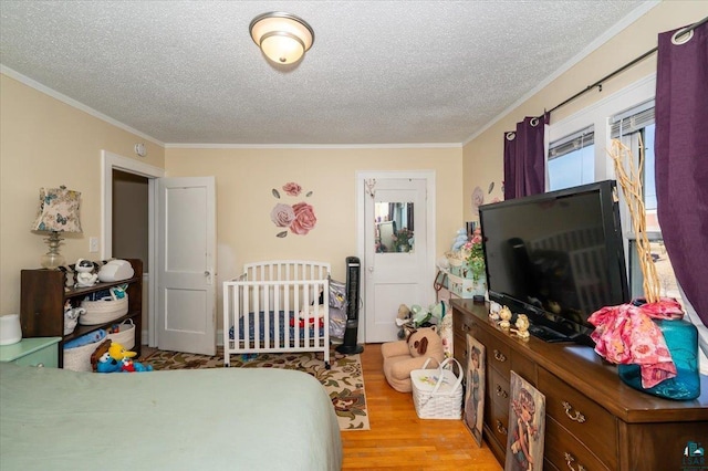 bedroom featuring ornamental molding, a textured ceiling, and wood finished floors