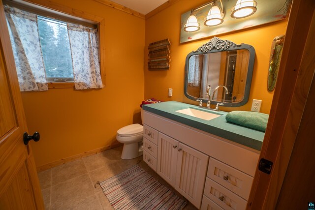 bathroom with tile patterned flooring, toilet, vanity, and baseboards