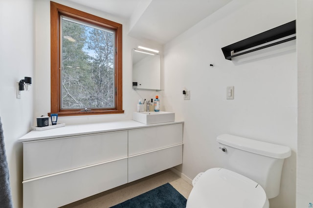 bathroom featuring toilet, vanity, and baseboards