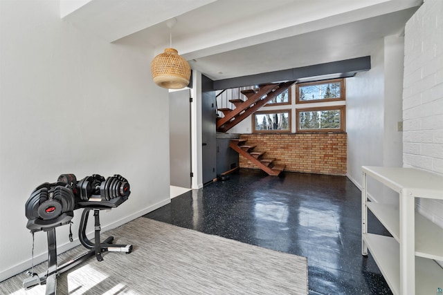 exercise area with baseboards and brick wall