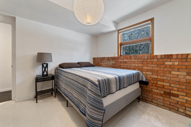 bedroom with brick wall and baseboards