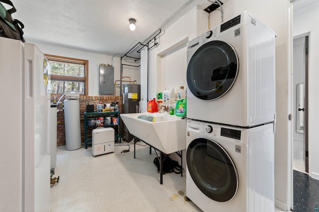 laundry room with laundry area, electric panel, water heater, a sink, and stacked washer / drying machine