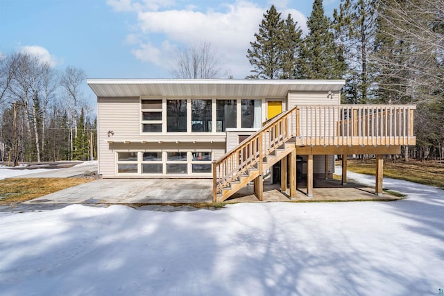 view of front of home with stairway, an attached garage, and a wooden deck