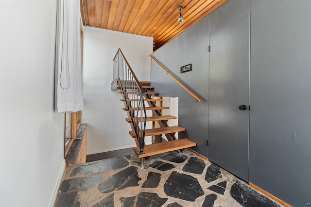 stairs featuring stone finish flooring, baseboards, and wood ceiling