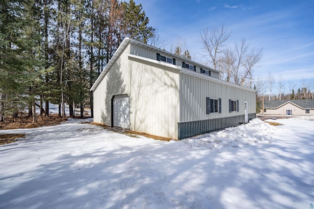 view of snow covered exterior featuring an outdoor structure and a detached garage