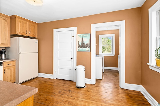 kitchen with light countertops, baseboards, light wood-type flooring, and freestanding refrigerator